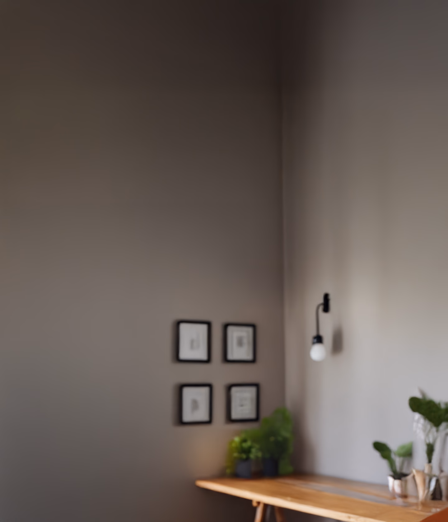 Softly lit, home office background with a plant, dresser, and framed certificates on the wall.